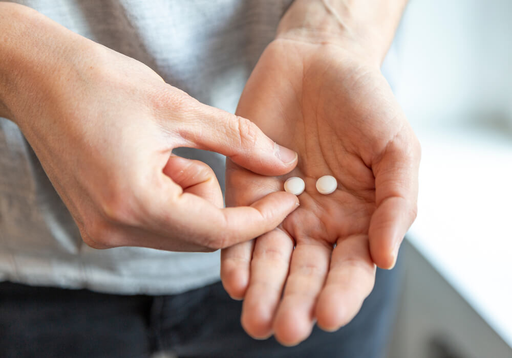Frau mit zwei Tabletten in der Hand