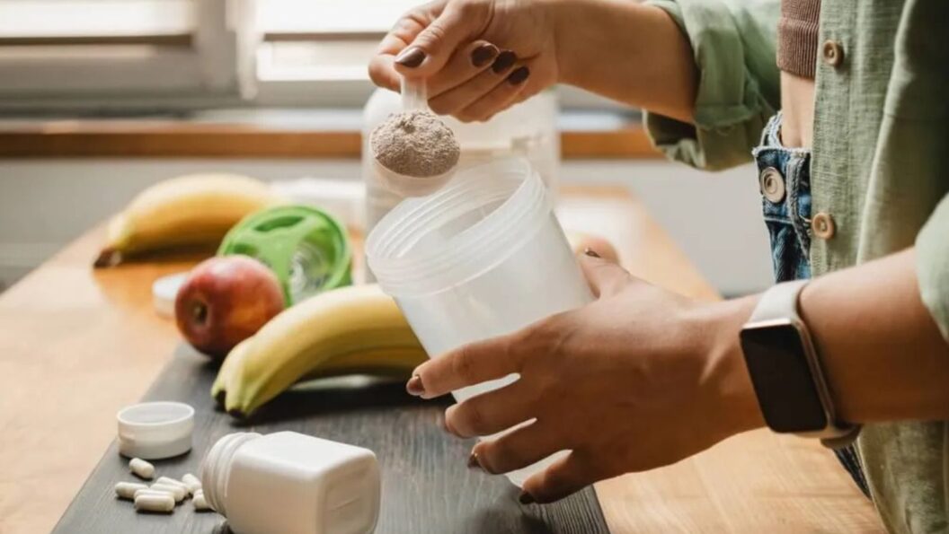 Frau macht sich einen Shake mit Kreatin-Pulver