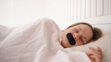 Zum Artikel: Mouth Taping: Frau mit Mundpflaster beim Schlafen