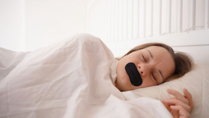 Mouth Taping: Frau mit Mundpflaster beim Schlafen
