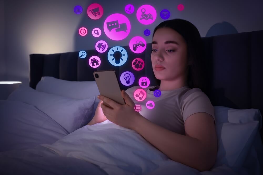 Smartphone-Sucht: Frau abens im Bett mit Smartphone